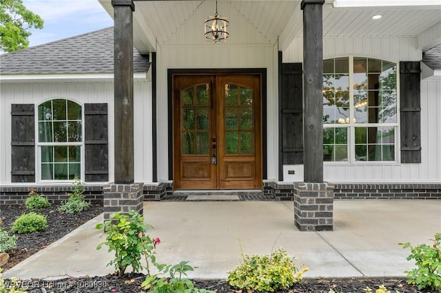 entrance to property with a porch, french doors, and a shingled roof