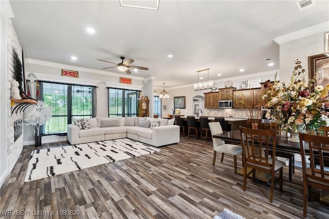 living area with crown molding, visible vents, ceiling fan with notable chandelier, and recessed lighting