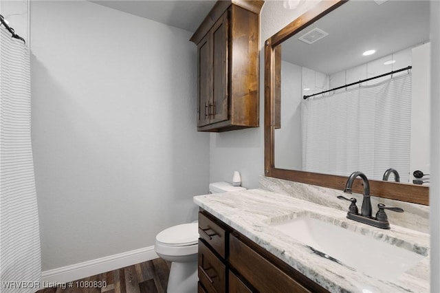 bathroom featuring baseboards, toilet, visible vents, vanity, and wood finished floors