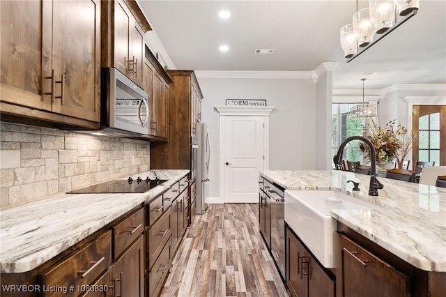 kitchen featuring a sink, light stone counters, visible vents, light wood finished floors, and appliances with stainless steel finishes