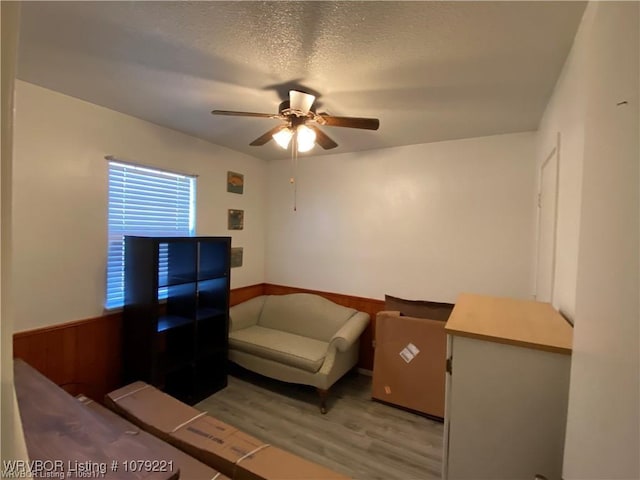 bedroom with light wood-style floors, ceiling fan, and a textured ceiling