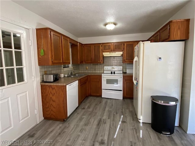 kitchen featuring white appliances, backsplash, and light wood-style floors