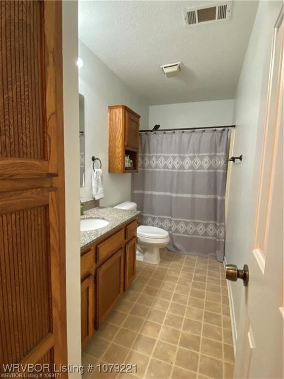 bathroom with a textured ceiling, tile patterned flooring, toilet, vanity, and visible vents