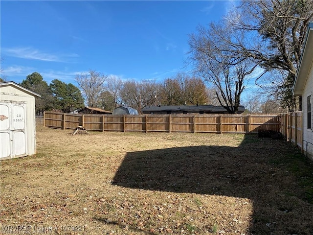 view of yard with a fenced backyard, a shed, and an outbuilding