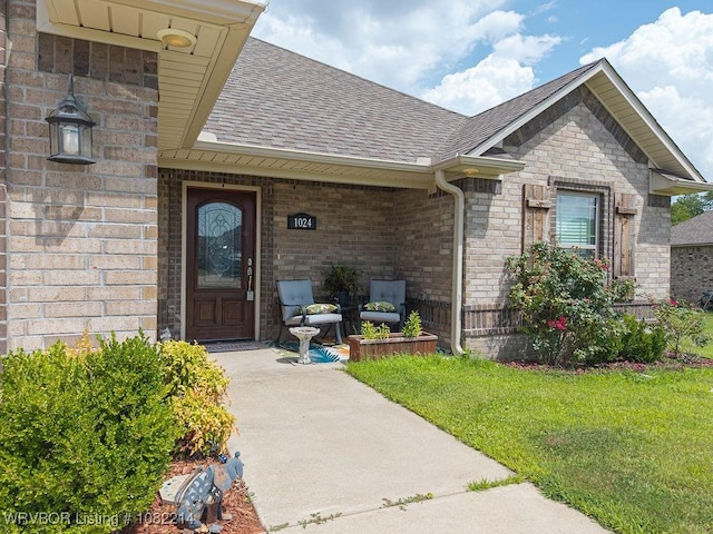 1024 Mourning Dove Way, Barling, AR 72923 - doorway to property with roof with shingles, brick siding, a lawn, and covered porch
