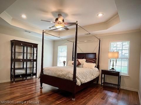 bedroom featuring ornamental molding, multiple windows, and a raised ceiling