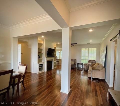 living room featuring a barn door, a fireplace, crown molding, and dark wood-type flooring