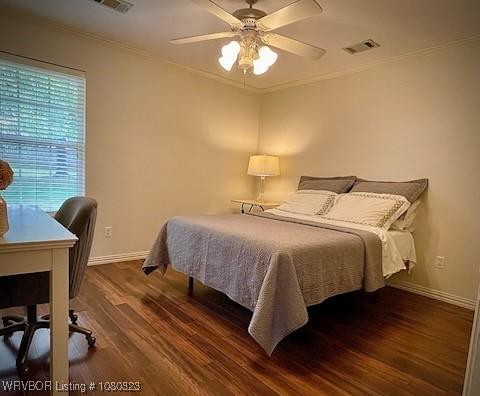 bedroom with wood finished floors, visible vents, ornamental molding, and baseboards