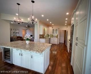 kitchen with light stone counters, an inviting chandelier, white cabinetry, and dark wood-type flooring