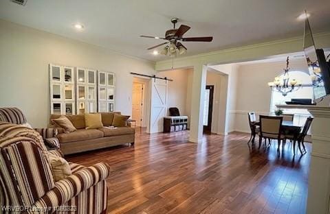 living area featuring a barn door, dark wood-style flooring, recessed lighting, ornamental molding, and ceiling fan with notable chandelier