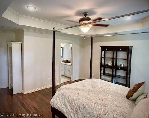 bedroom with a raised ceiling, ensuite bath, crown molding, baseboards, and wood finished floors