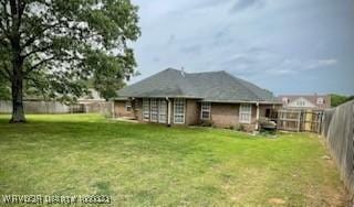 rear view of house with a yard and a fenced backyard
