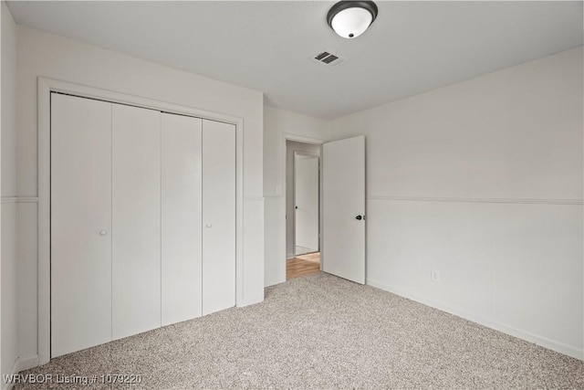 unfurnished bedroom featuring light colored carpet, a closet, and visible vents