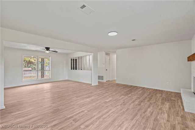 unfurnished living room featuring a brick fireplace, baseboards, visible vents, and light wood finished floors