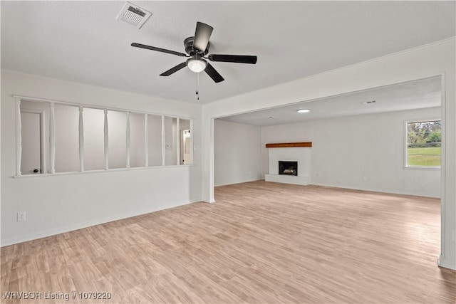 unfurnished living room with visible vents, baseboards, light wood-style flooring, ceiling fan, and a brick fireplace