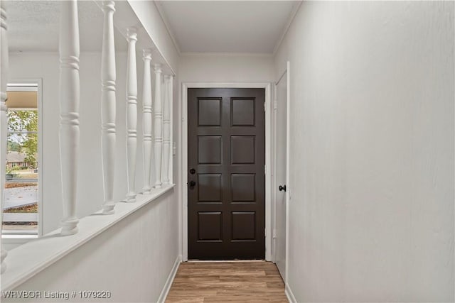 entryway with ornamental molding, light wood-style flooring, and baseboards