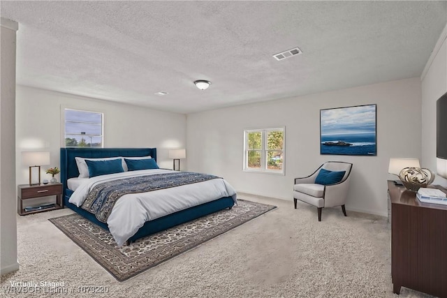 bedroom with visible vents, light carpet, and a textured ceiling