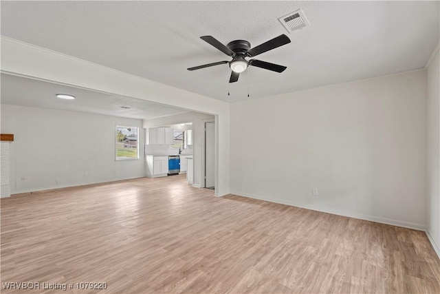 unfurnished living room featuring ceiling fan, light wood-style flooring, visible vents, and baseboards