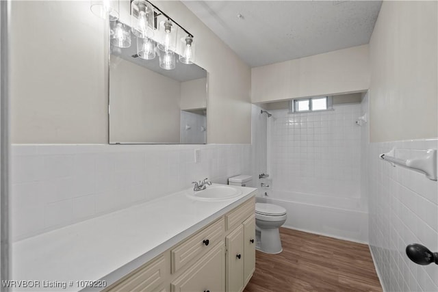 full bath featuring a wainscoted wall, tile walls, toilet, vanity, and wood finished floors