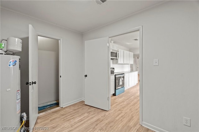 empty room with light wood-type flooring, baseboards, visible vents, and gas water heater