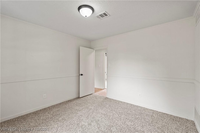 spare room featuring carpet flooring, visible vents, and crown molding