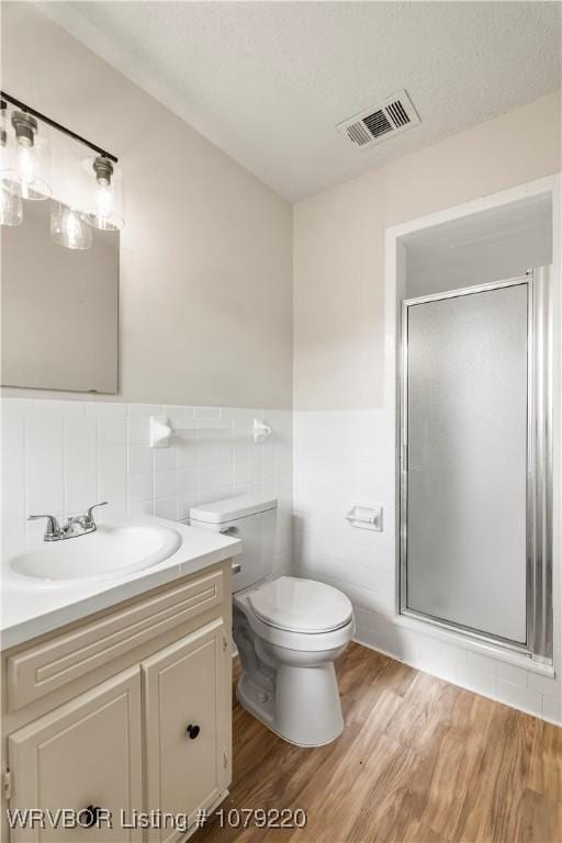 bathroom with a stall shower, visible vents, vanity, and wood finished floors