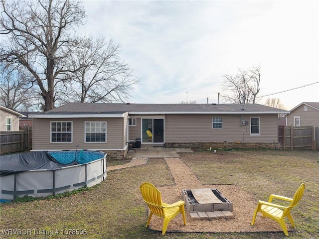 back of property featuring a fire pit, a lawn, a patio, and a covered pool