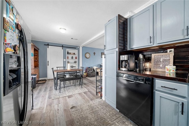 kitchen featuring dishwasher, a barn door, stainless steel fridge, and light wood-type flooring