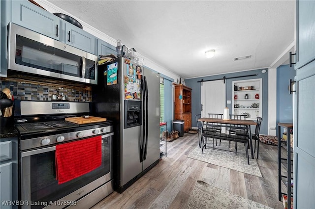 kitchen featuring hardwood / wood-style floors, a barn door, a textured ceiling, and appliances with stainless steel finishes