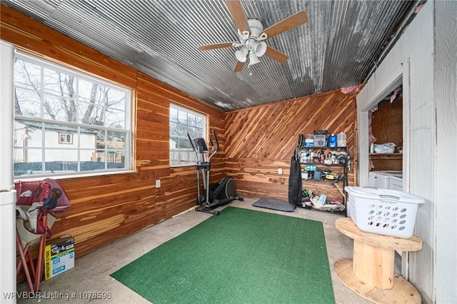 exercise room featuring ceiling fan and wood walls