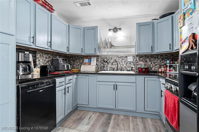 kitchen with sink, dishwasher, tasteful backsplash, a textured ceiling, and light wood-type flooring