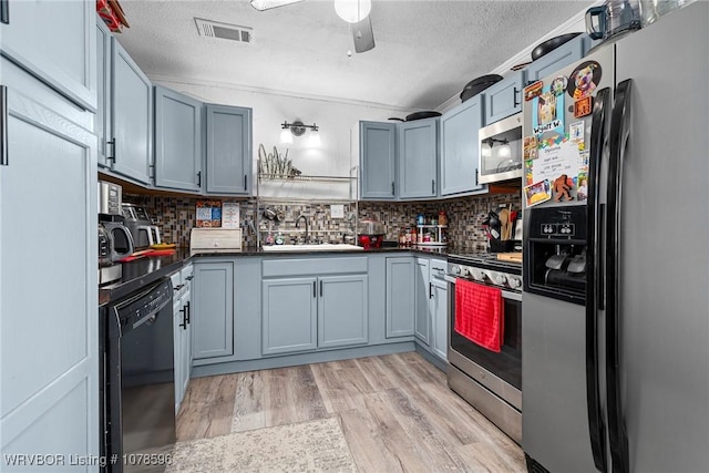 kitchen with stainless steel appliances, sink, backsplash, and light hardwood / wood-style flooring