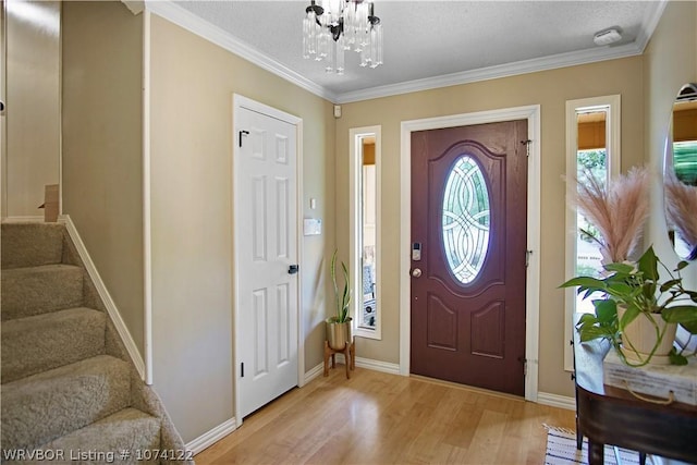 entryway featuring an inviting chandelier, ornamental molding, and light wood-type flooring