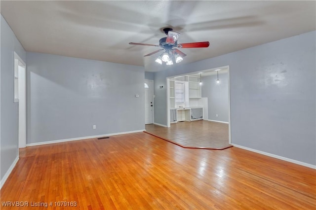 empty room featuring ceiling fan, light wood-type flooring, visible vents, and baseboards