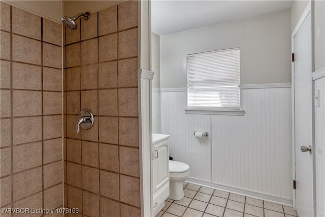 bathroom with toilet, a wainscoted wall, vanity, a tile shower, and tile patterned floors