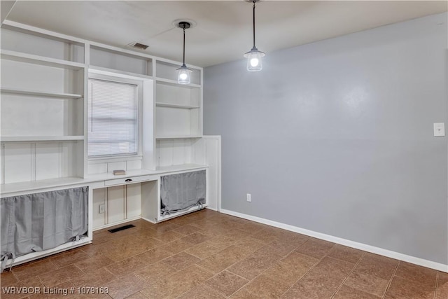 unfurnished office with built in desk, visible vents, and baseboards