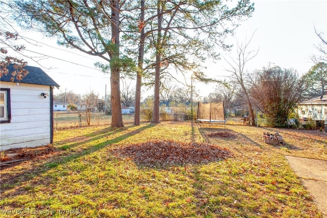 view of yard featuring a trampoline and fence