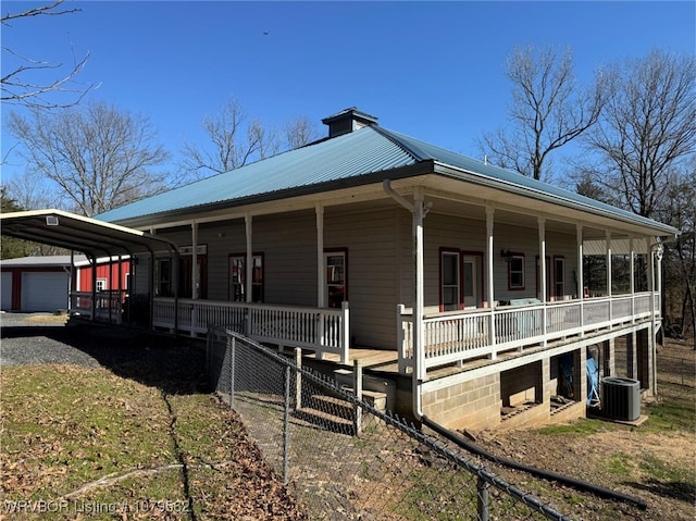 view of side of home with an outbuilding, driveway, covered porch, central AC, and metal roof