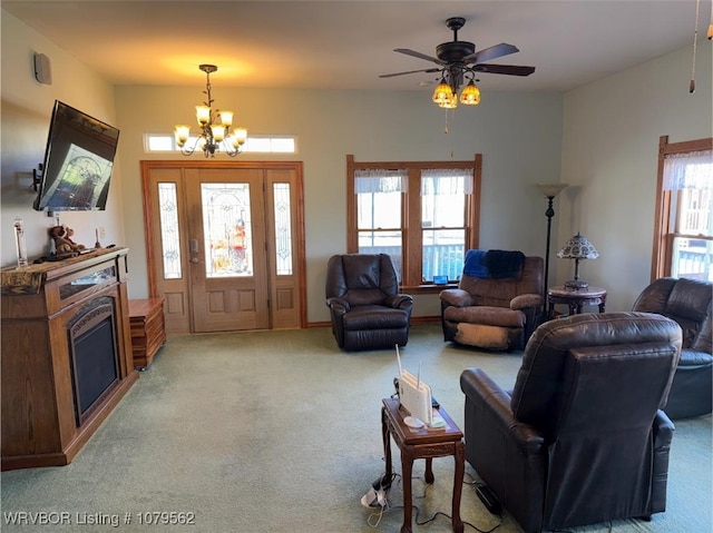 living room featuring light carpet, ceiling fan with notable chandelier, and a fireplace