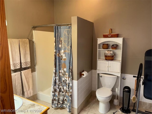 bathroom featuring toilet, wainscoting, a shower with curtain, tile patterned floors, and tile walls