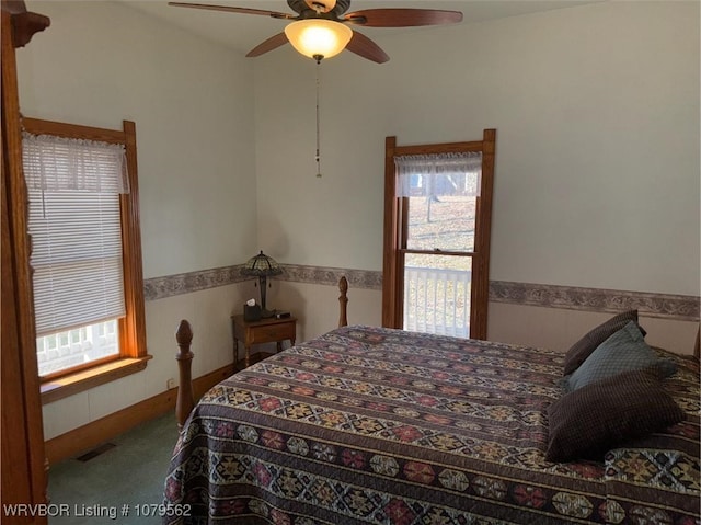 bedroom with ceiling fan, visible vents, carpet floors, and a wainscoted wall