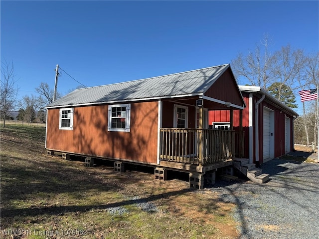 view of property exterior with a garage, gravel driveway, and metal roof