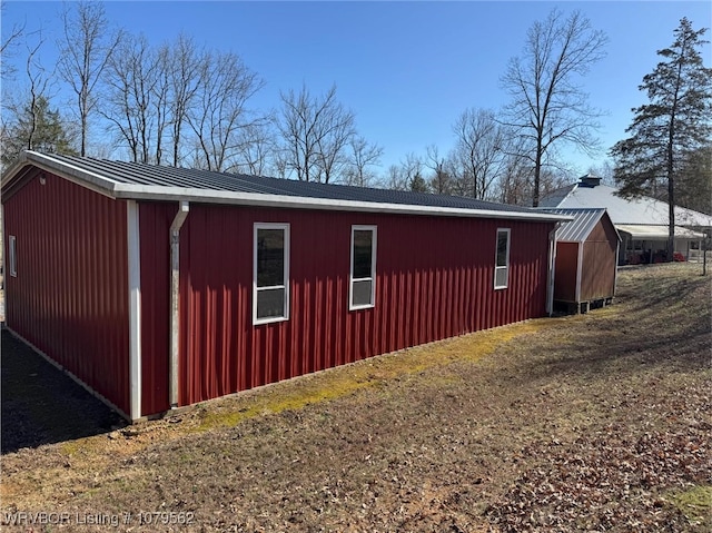 view of property exterior with an outbuilding, metal roof, and a standing seam roof