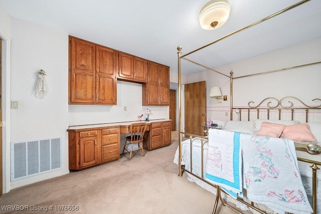 carpeted bedroom featuring built in desk