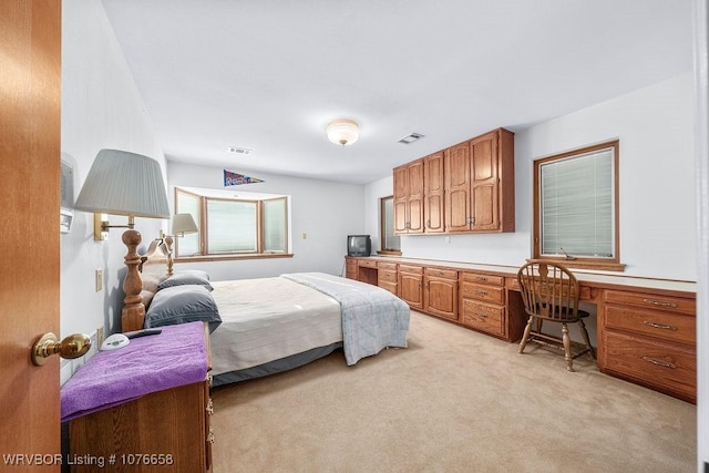 bedroom featuring light colored carpet and built in desk