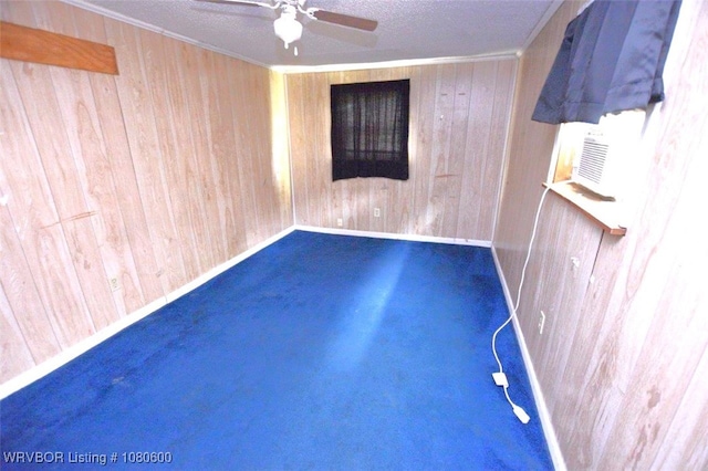 unfurnished room with a ceiling fan, wooden walls, a textured ceiling, and crown molding
