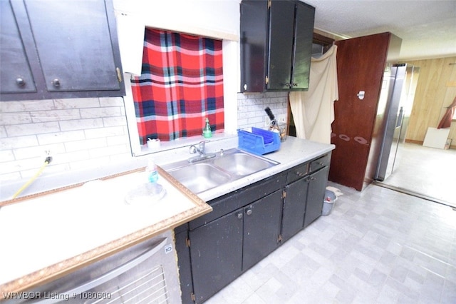 kitchen with tasteful backsplash, stainless steel refrigerator with ice dispenser, light countertops, and a sink