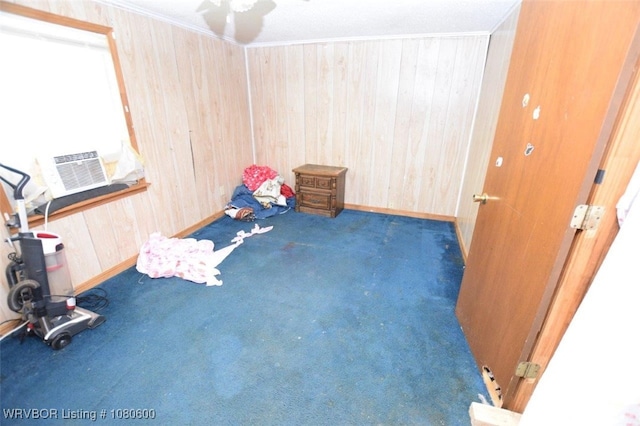 interior space featuring wood walls, crown molding, baseboards, and carpet floors