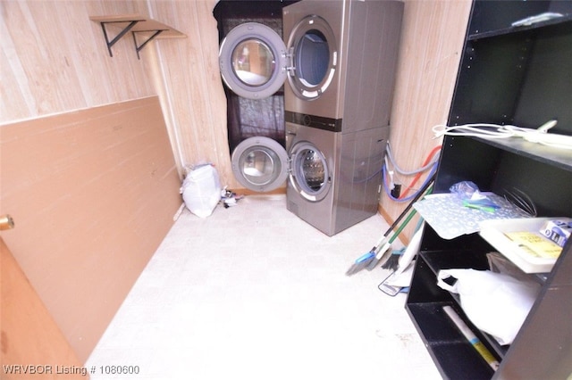 washroom featuring stacked washer and clothes dryer, wood walls, and laundry area