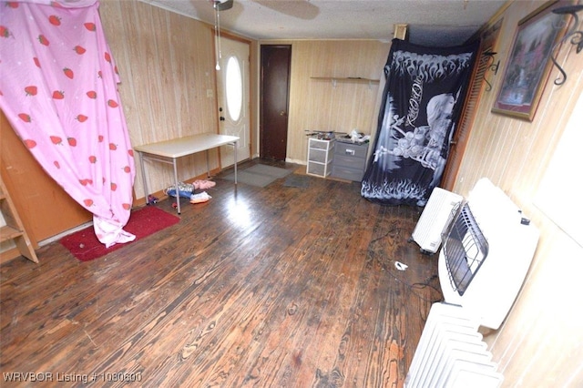 mudroom featuring radiator, a ceiling fan, wooden walls, and wood finished floors